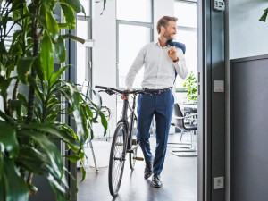 Mann verlässt mit seinem Fahrrad sein Büro