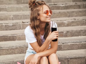 Eine Frau sitzt mit einer Limonade auf einer Treppe