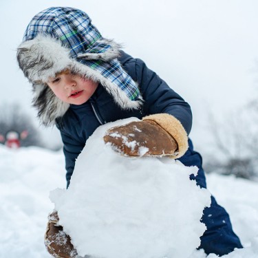 Kleiner Junge baut einen Schneemann