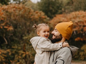 Ein Vater mit seiner Tochter auf dem Arm in einer Herbstlandschaft