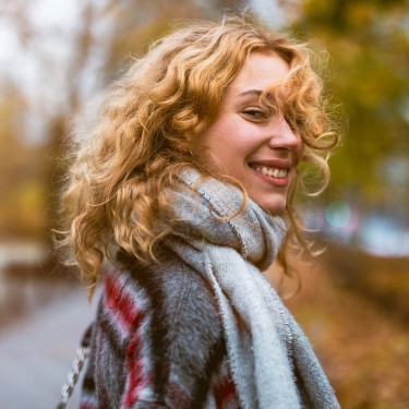 Krankenversicherung, so wie du sie brauchst Junge Frau mit Schal läuft durch eine Herbstlandschaft