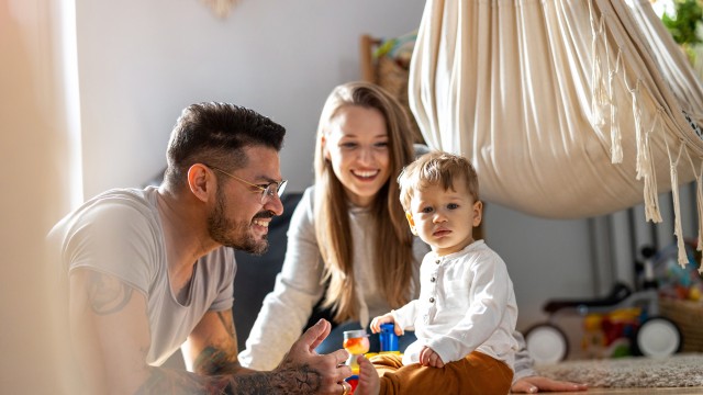 Eine junge Familie sitzt auf dem Boden und spielt. 