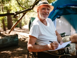 Ein älterer Mann sitzt vor seinem Zelt im Campingstuhl